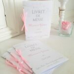 plusieurs livret de messe blanc avec ruban rose sur une table blanche