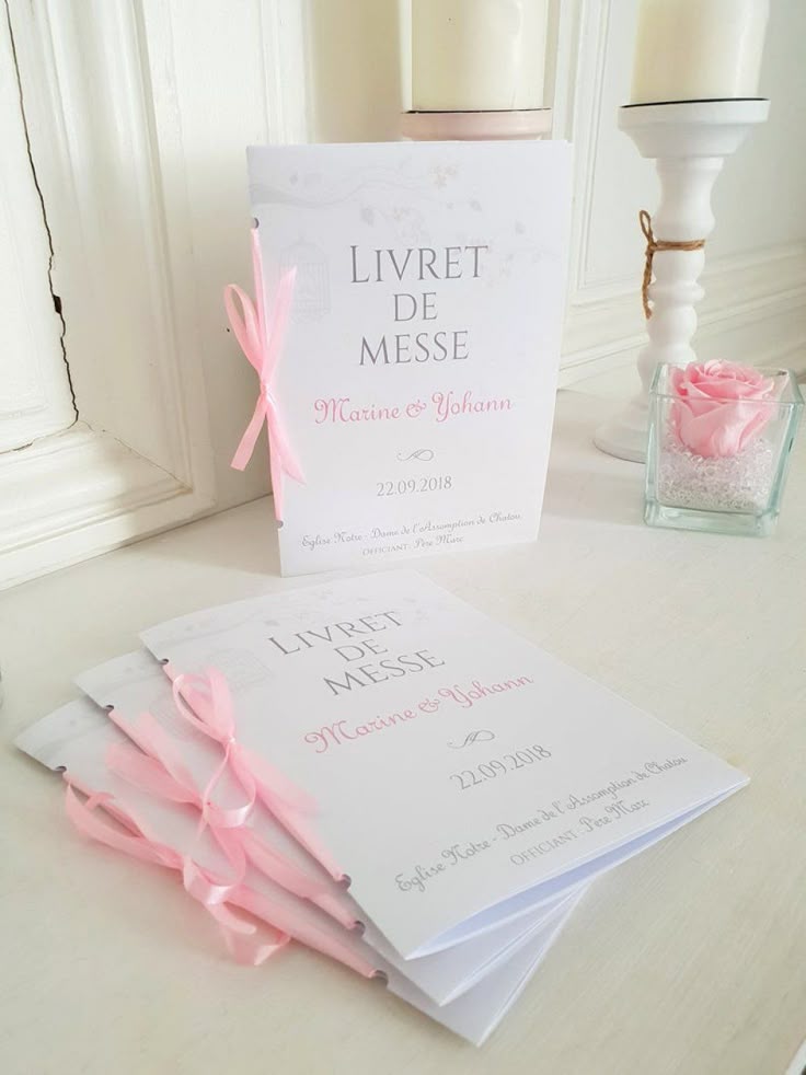 plusieurs livret de messe blanc avec ruban rose sur une table blanche