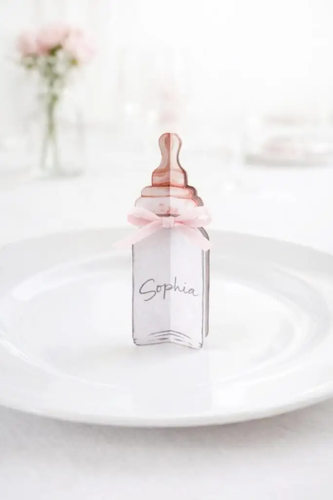 marque place en papier en forme de biberon avec ruban rose