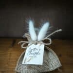 dragées de mariage personnalisés avec un sachet en toile de jute, des queues de lapin et une corde pour attacher une magnifique étiquette 100% personnalisée sur papier épais cartonné avec un visuel bohème. Le pochon est posé sur du bois